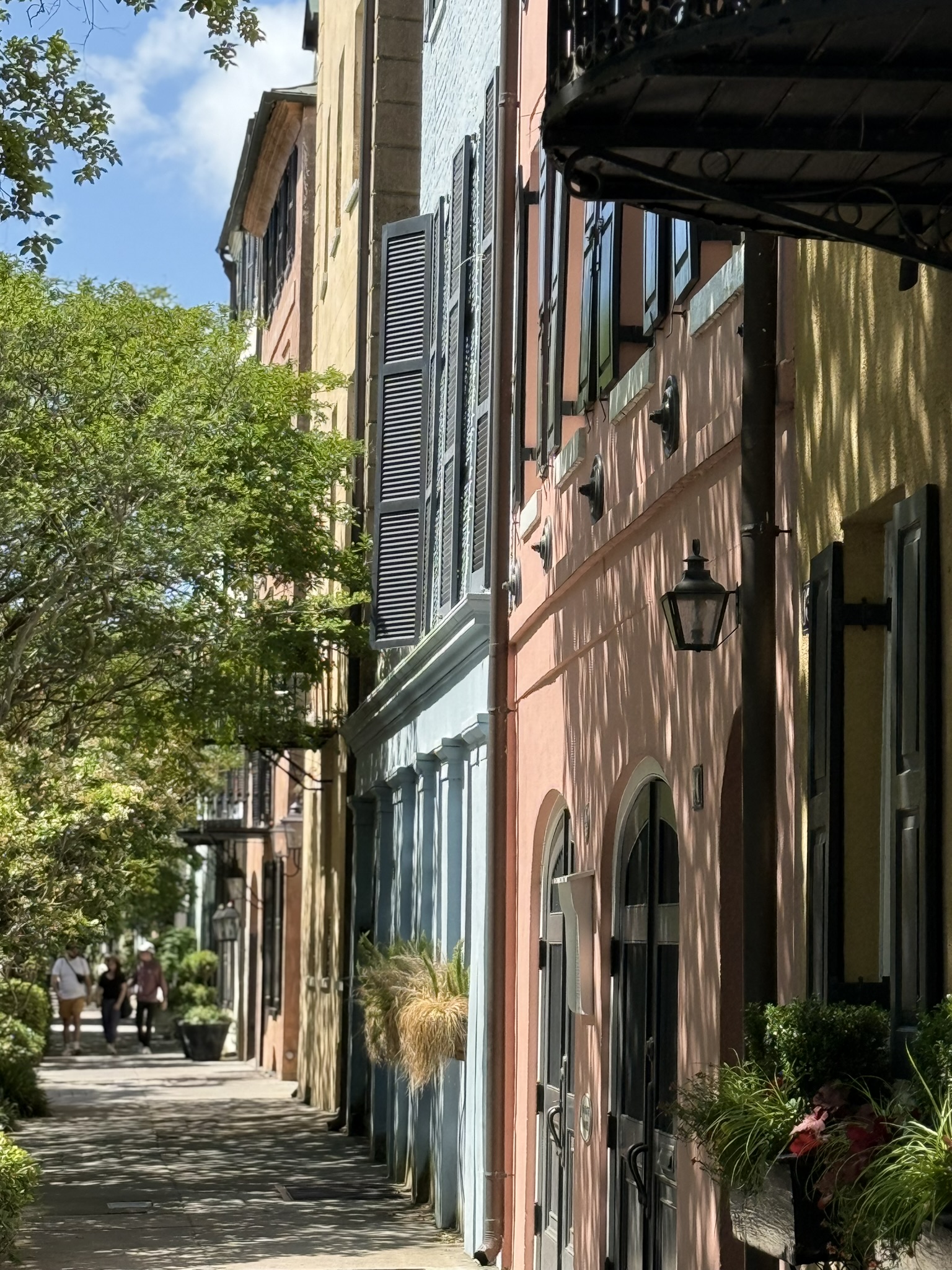 Brightly painted houses of yellow, pink, and blue all lined up next to each other at Rainbow Row in Charleston, SC