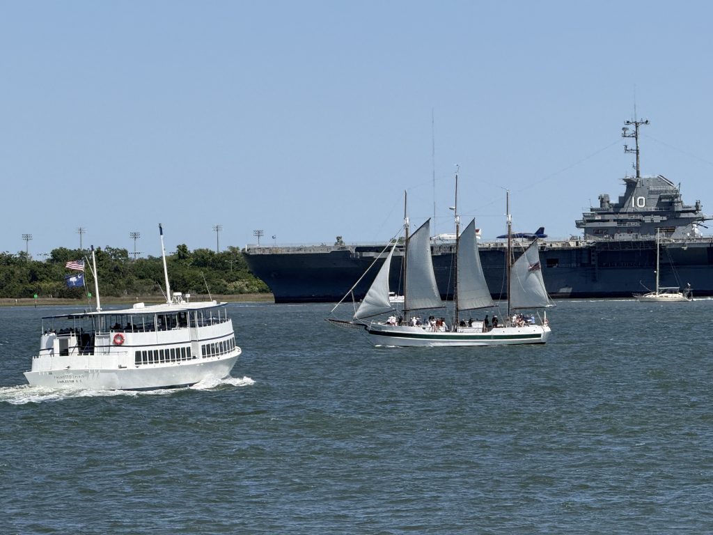 Charleston, South Carolina Harbor as seen from Waterfront Park in Charleston, SC with the USS Yorktown, a ferry and a large sail boat.