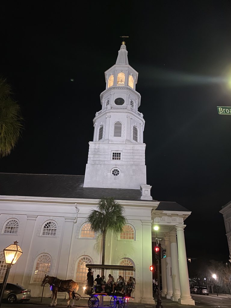 Old Church at night in Charleston, SC with palm tree and horse drawn carriage in front of church