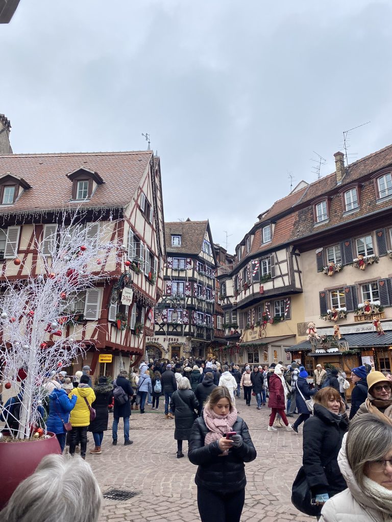 Colmar hidden Christmas Courtyard with people walking and Christmas decorations seen down the street of the old village