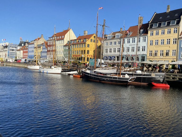 Beautiful picture of the bright colored buildings in Nyhavn lining the canal surrounded by bright blue sky in Copenhagen unique experiences
