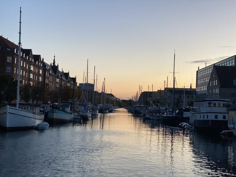 Sunsetting in the distance. Canal lined with boats and buildings to each side