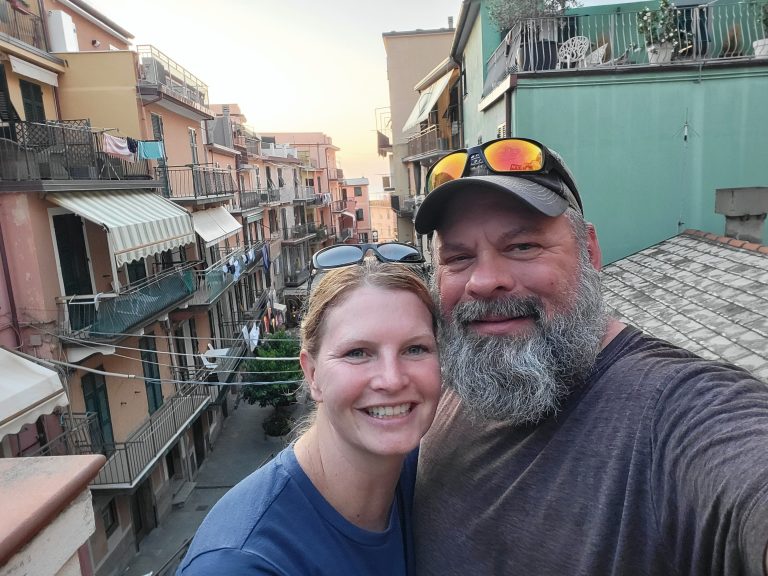 Hidden spots in Cinque Terre, Italy shot of Casey and Mark with village below in the background
