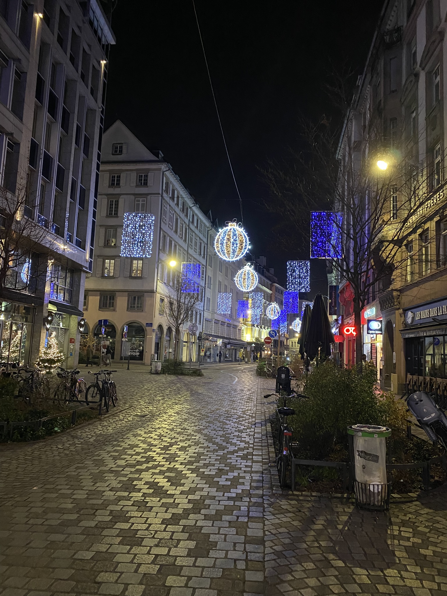 Strasboug Christmas Market street at night with large Christmas lights hanging in middle of street