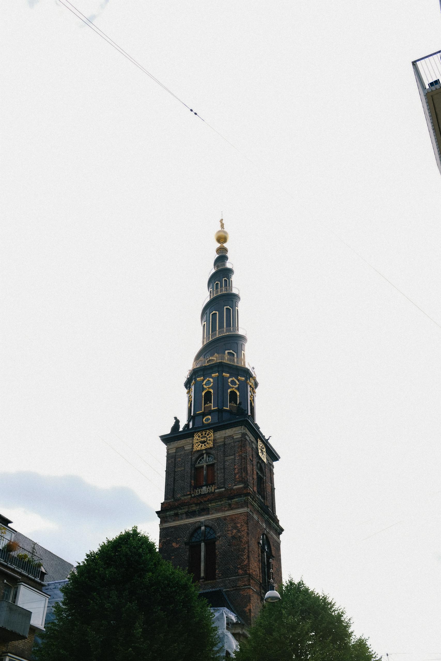 Low angle view of the iconic Church of Our Savior tower in Copenhagen, Denmark against a grey sky.