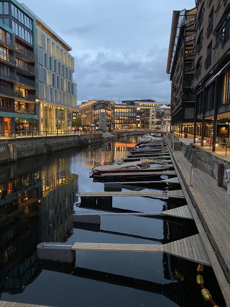 Oslo at night. District by the waterfront showing buildings and waterway with boats docked.