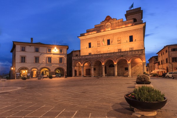 As night falls an old store front in a village square in a small towns in Italy