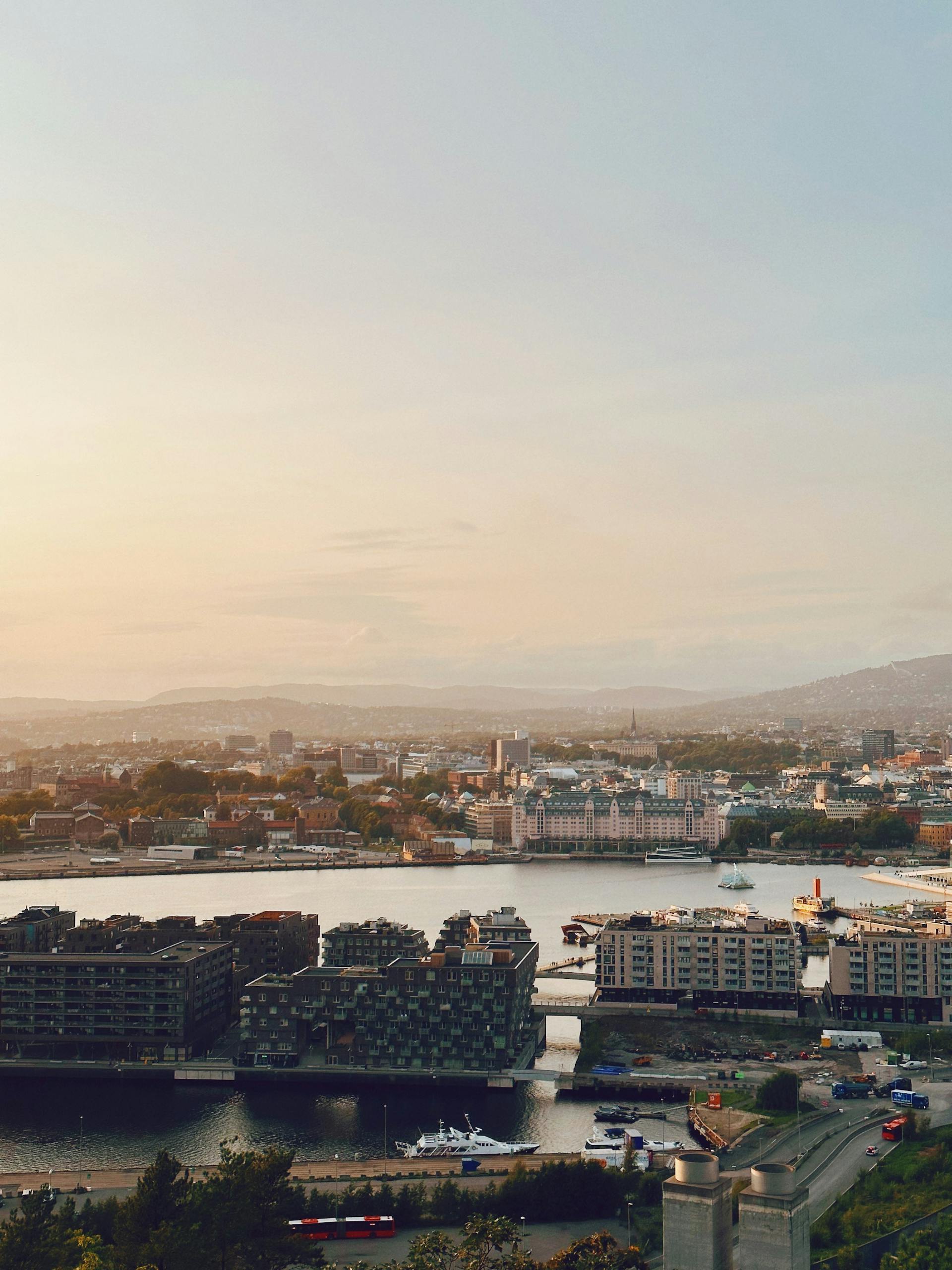 A breathtaking aerial view of Oslo's waterfront area at sunset, capturing the vibrant cityscape and serene fjord.