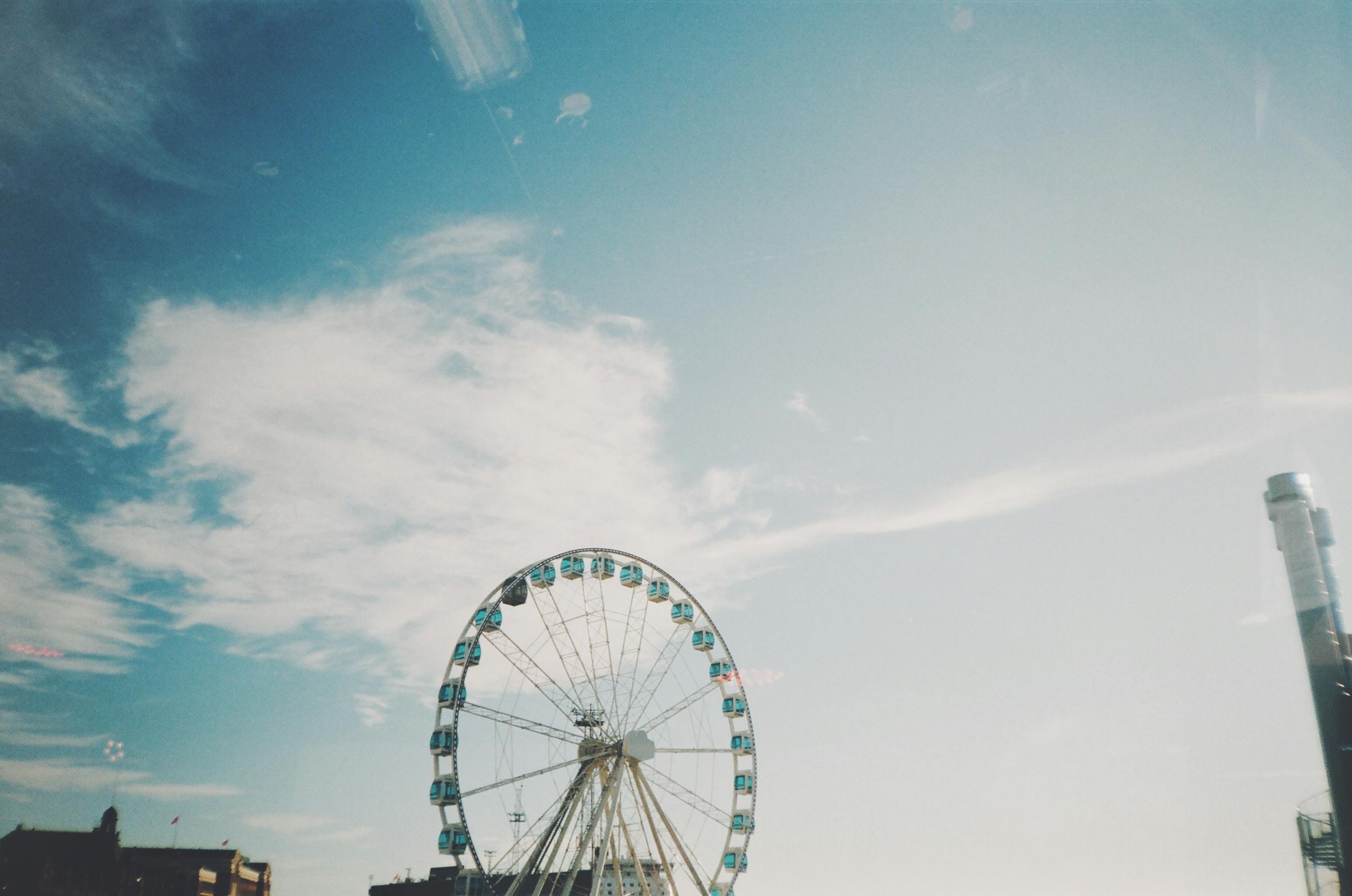 A large ferris wheel set against a bright blue sky with clouds in Helsinki, Finland.