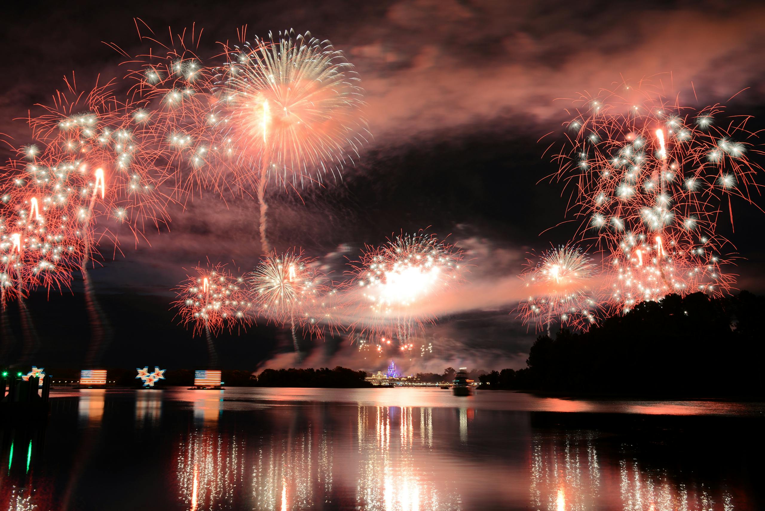 Dazzling fireworks light up the night sky over Lake Buena Vista, FL, creating a stunning reflection on the water.