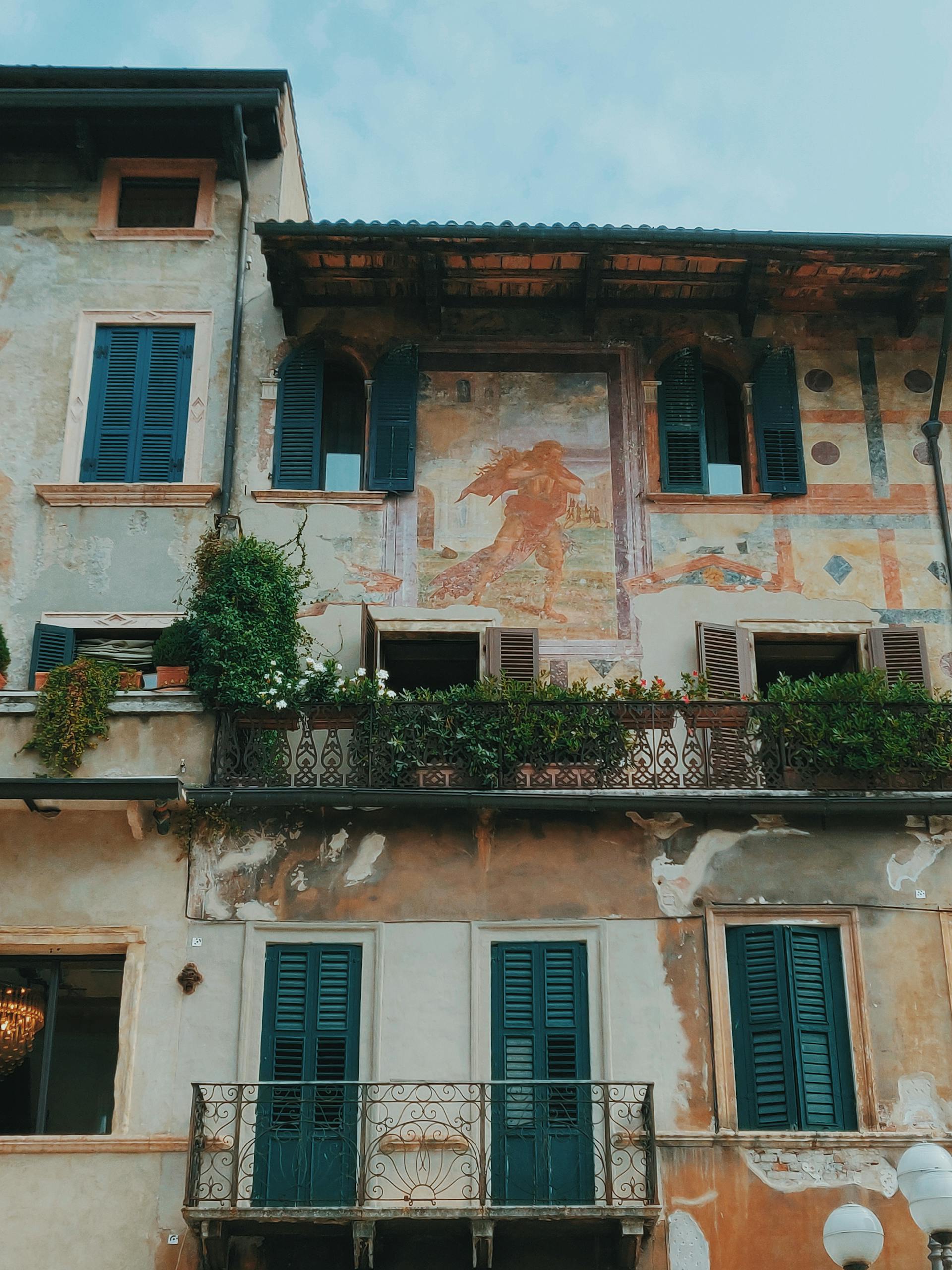 Historic building with a vintage mural and colorful shutters in European town.