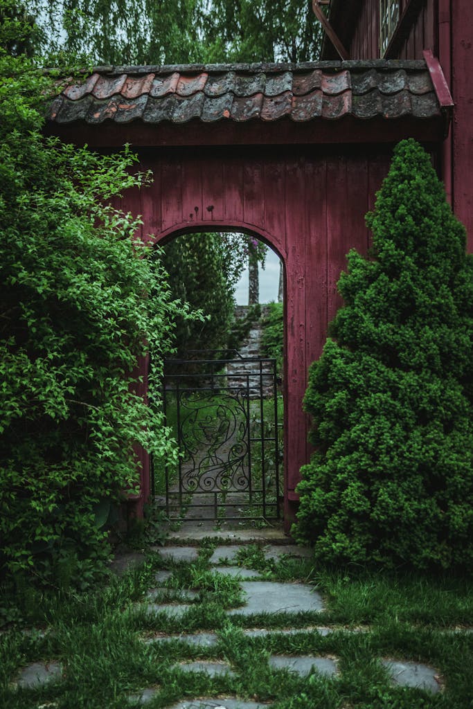 Rustic red garden gate surrounded by lush green foliage in a tranquil setting in romantic spots in Oslo.