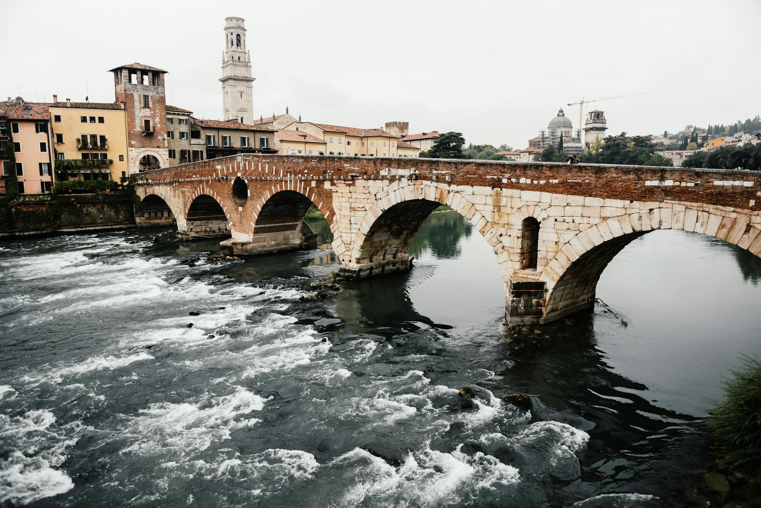 Scenic view of Ponte Pietra, a historic stone bridge in Verona, Italy, over the Adige River.