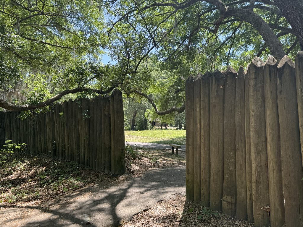 Charlestowne Landing on a summer day. You can see the replica of the old wall around Charlestowne as well as a walkway and a bench. This is located in Charleston, South Carolina