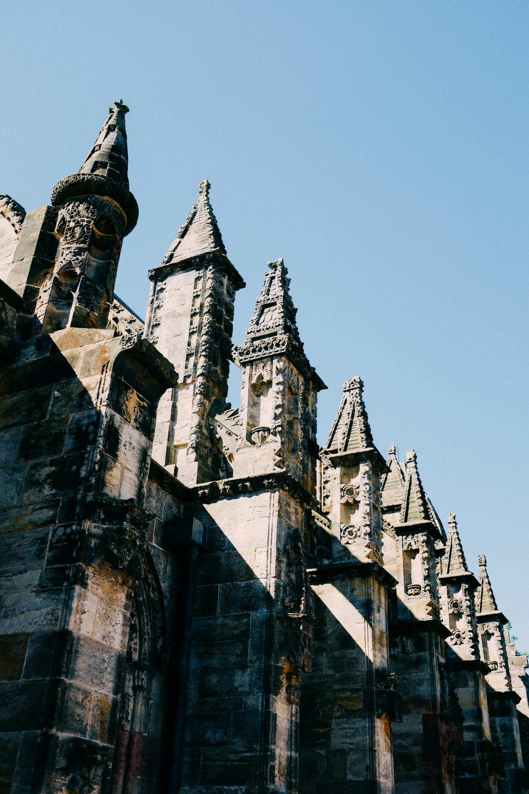 Low-angle shot of gothic architecture on a historic chapel facade under a clear blue sky in best day trips from Edinburgh