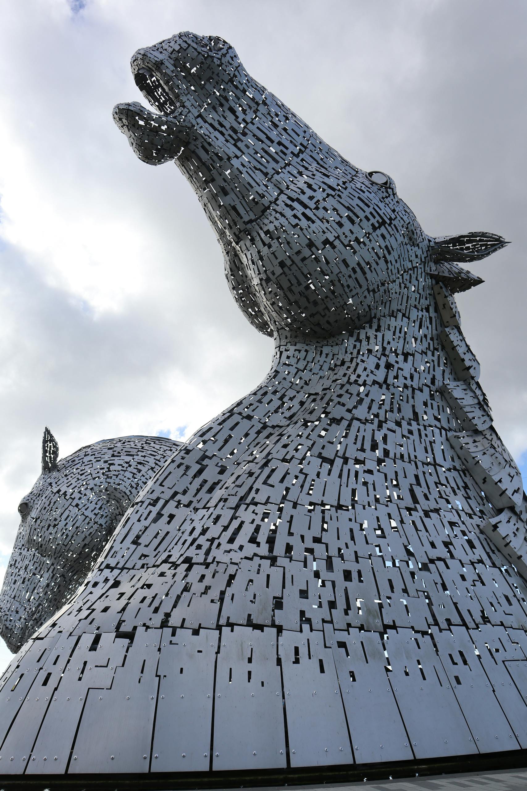 Stunning low angle view of The Kelpies sculptures against a cloudy sky in Falkirk, Scotland in best day trips from Edinburgh