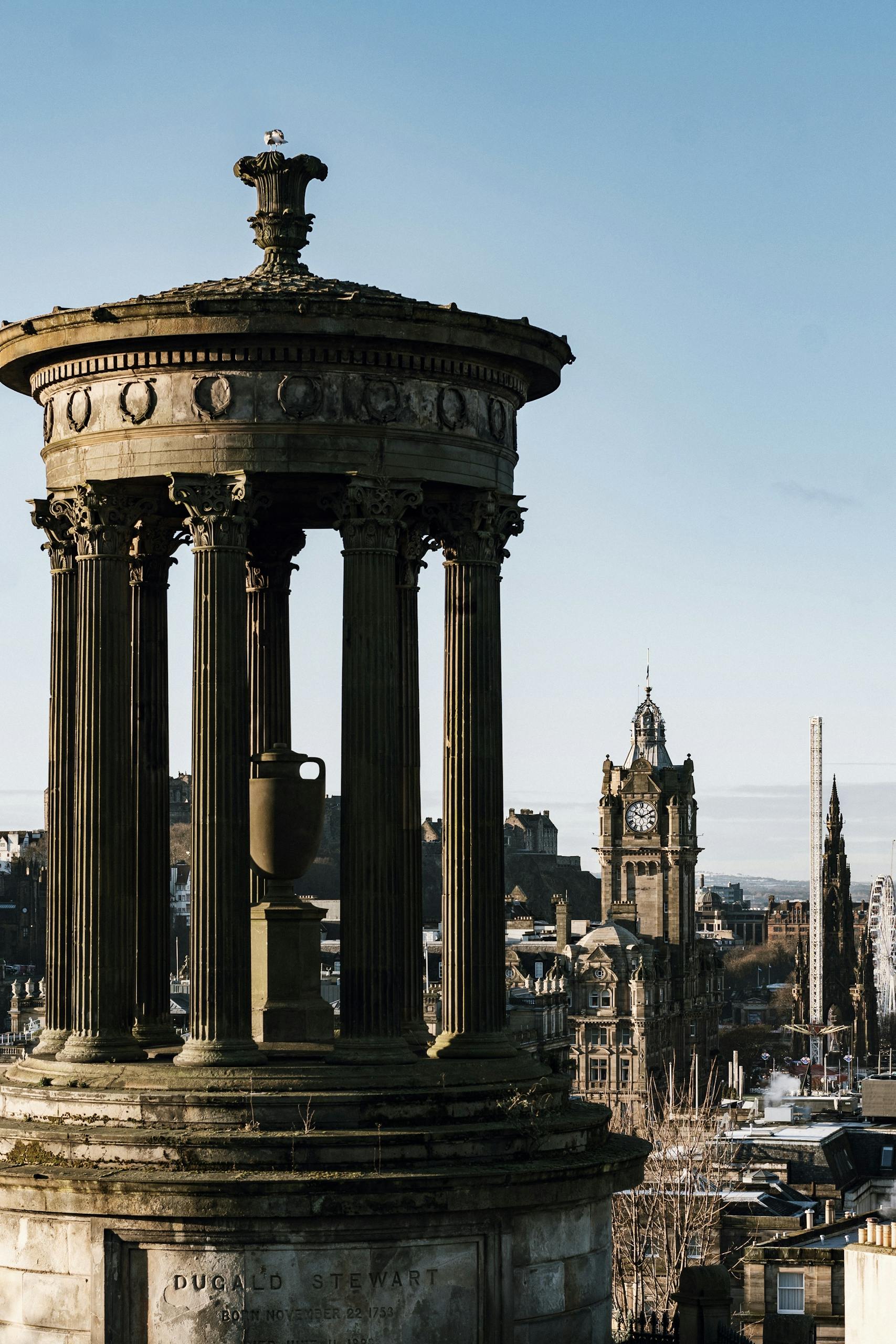 View of the Dugald Stewart Monument with Edinburgh skyline on a clear day.