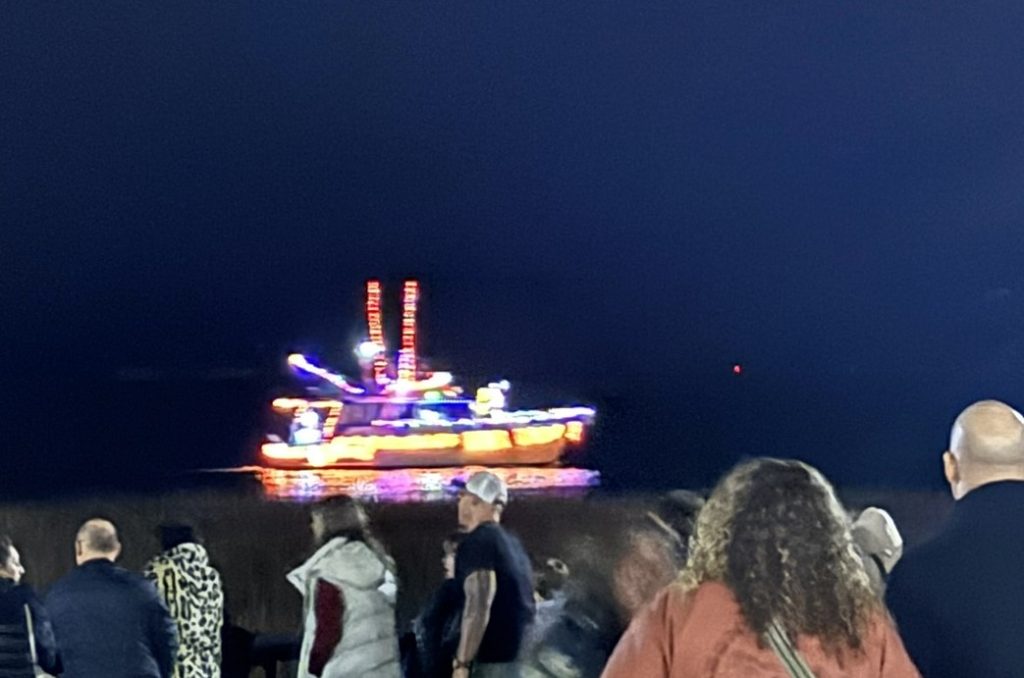 A boat adorned with Christmas lights cruising through Charleston harbor during the Christmas Boat Parade as seen during the best Christmas events in Charleston