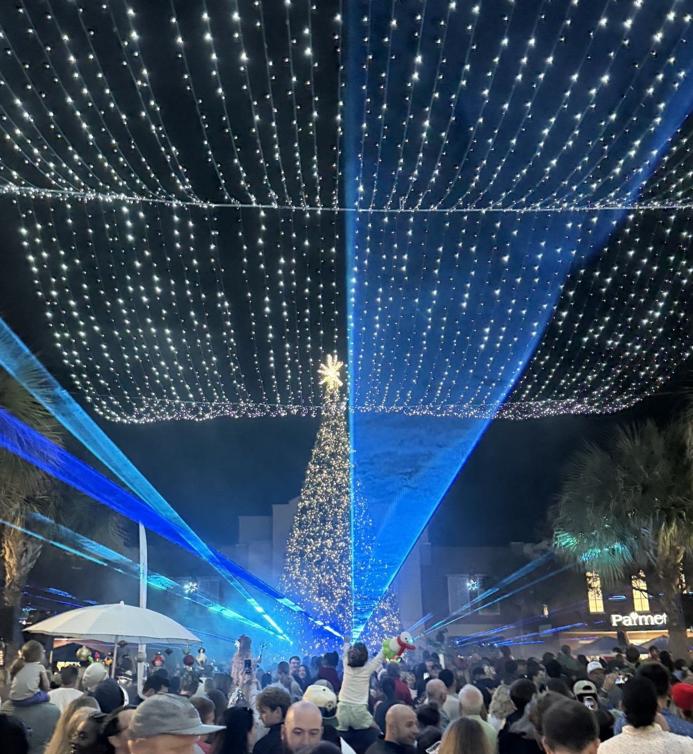 The tree lighting and laser show at the Mount Pleasant Town Centre with blue lasers a large lite tree and people in best Christmas events in Charleston, SC