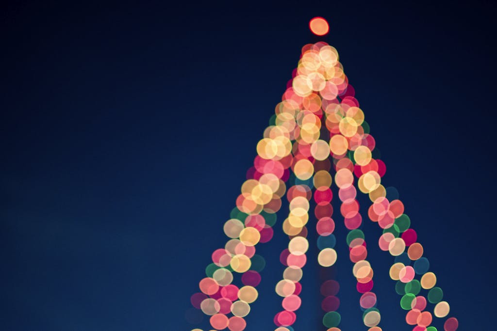 Colorful bokeh lights forming a Christmas tree against a dark blue sky in the best Christmas events in Charleston, SC