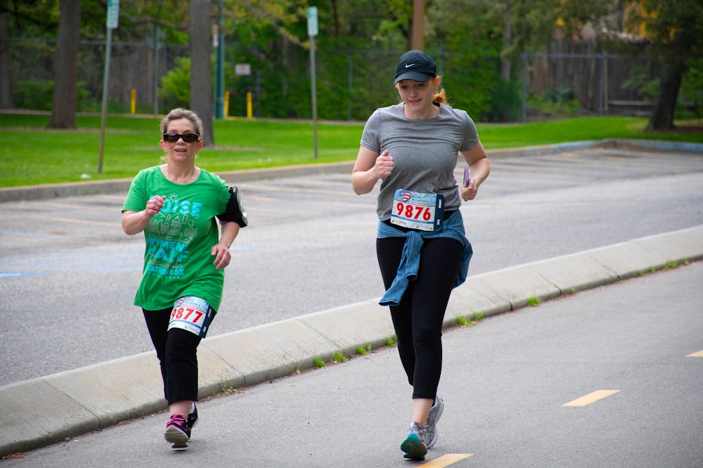 Two women jogging outdoors on a clear day, participating in a local race event.