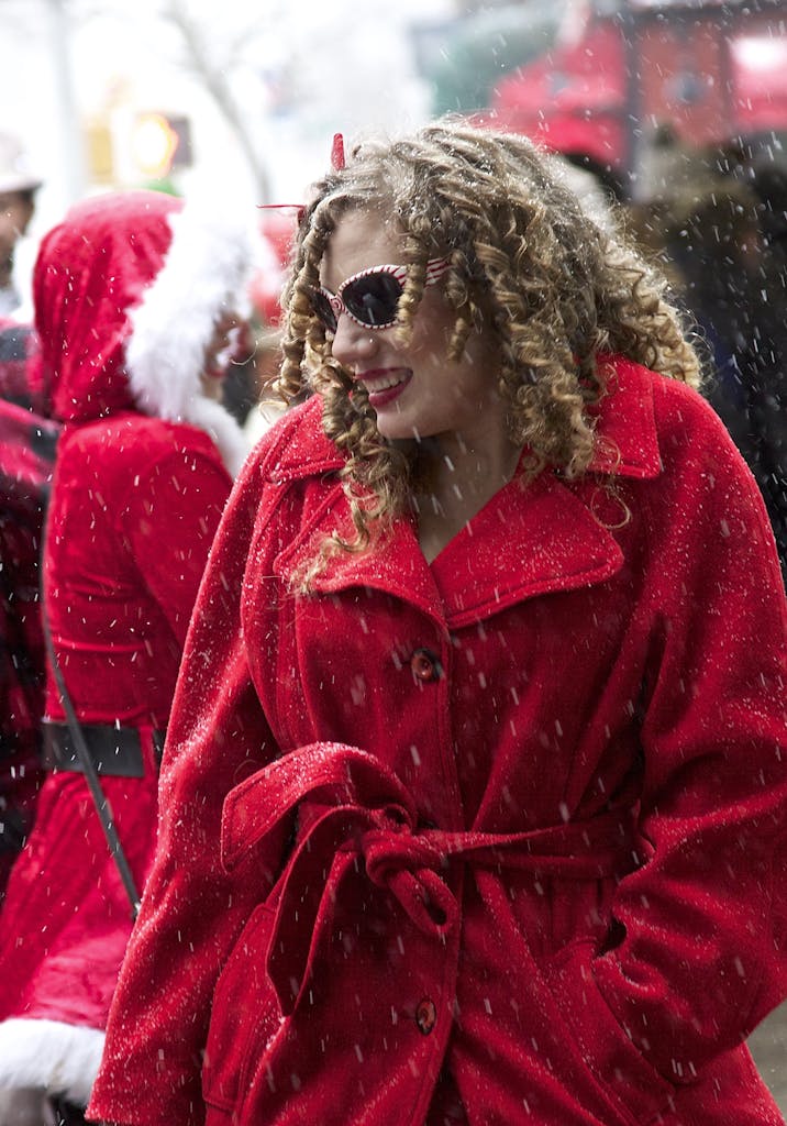 Woman in red coat enjoying a Christmas parade in the best Christmas events in Charleston, SC