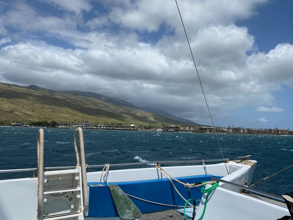 A picture from the boat while snorkeling in Maui. You can see the beautiful landscapes of the shore as well as the blue water.