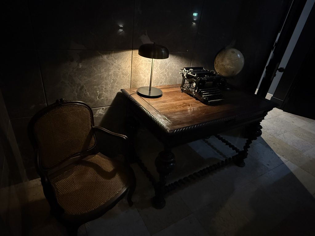 A decorative desk with lamp and globe on it inside the Historic Editory Riverside Santa Apolonia Hotel