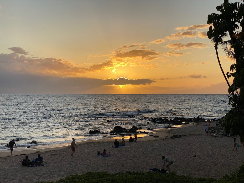 People on the beach as the sun is setting in Maui
