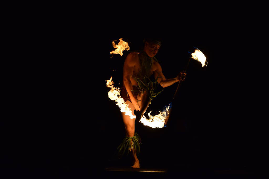 A captivating fire dancer performing a traditional Hawaiian dance at night in maui vs the big island