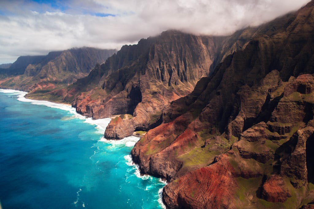 Stunning aerial view of the rugged Na Pali Coast, with dramatic cliffs and turquoise ocean in Hawaii.