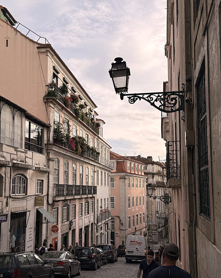 View down an urban street in the shopping district of Lisbon, Portugal in deciding which you should go to Lisbon vs Porto for couples.