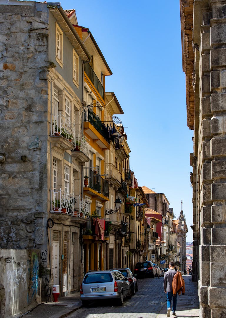 A scenic narrow street in Porto, Portugal, lined with historic buildings and cobblestone path on a sunny day when trying to figure out where to stay in Porto
