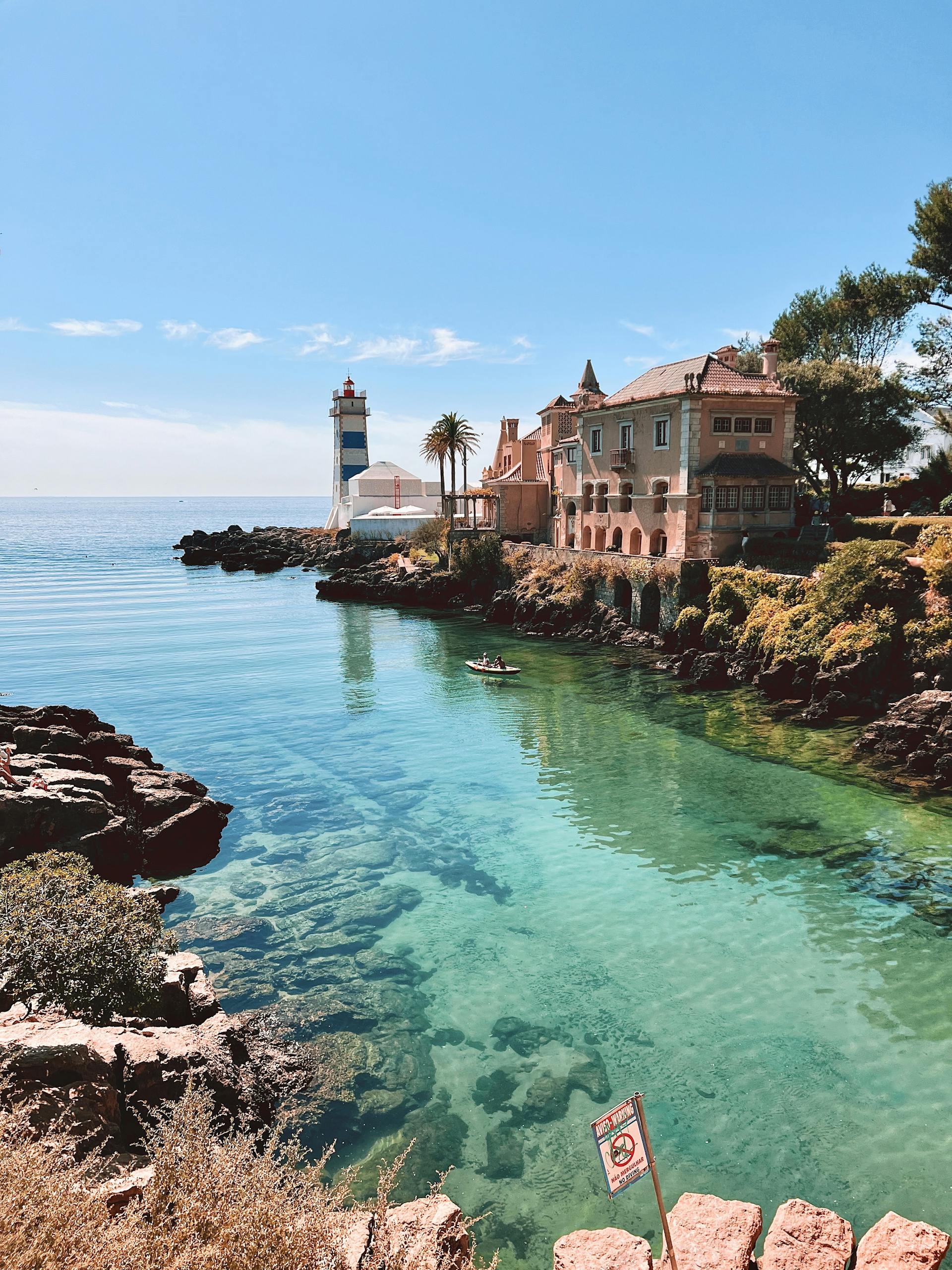 Picturesque Cascais coastline with a lighthouse and clear blue waters in best day trips from Lisbon.