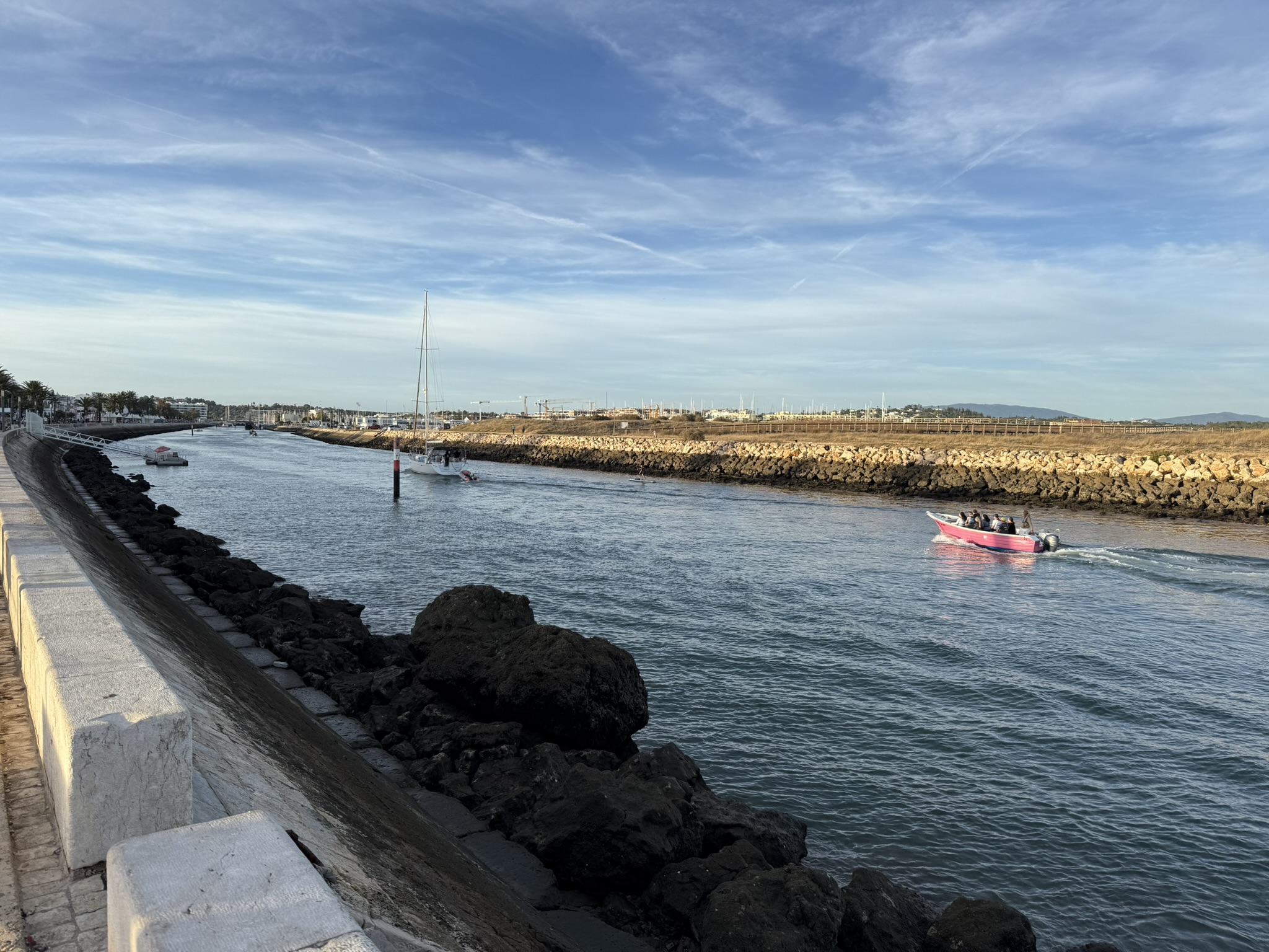 Small boat going down a waterway to a marina on spring break in the Algarves in Portugal as the sun is getting low in the sky on a beautiful day