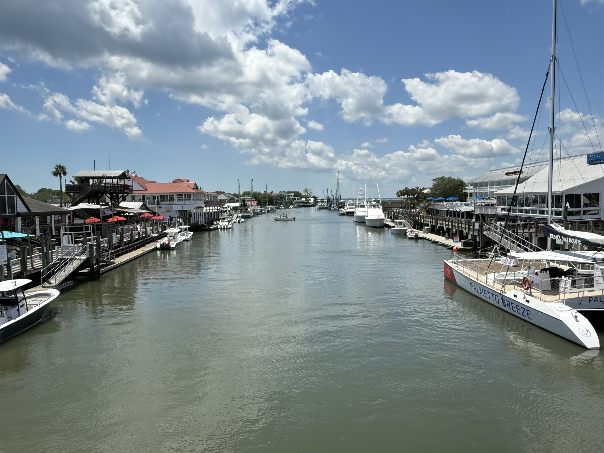 Shem Creek in Mount Pleasant, South Carolina with fishing boats and restaurants lined up on each side of the creek. This was seen on Spring Break in Charleston