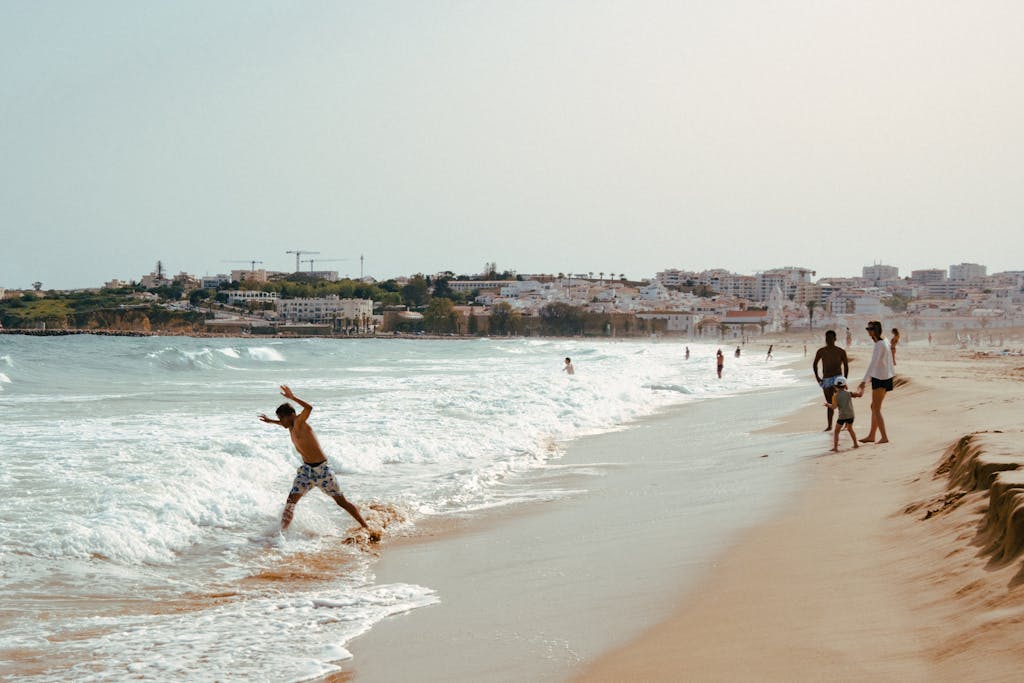 A lively summer day at Lagos beach in Portugal with families enjoying the waves and sunshine in the best algarve resorts