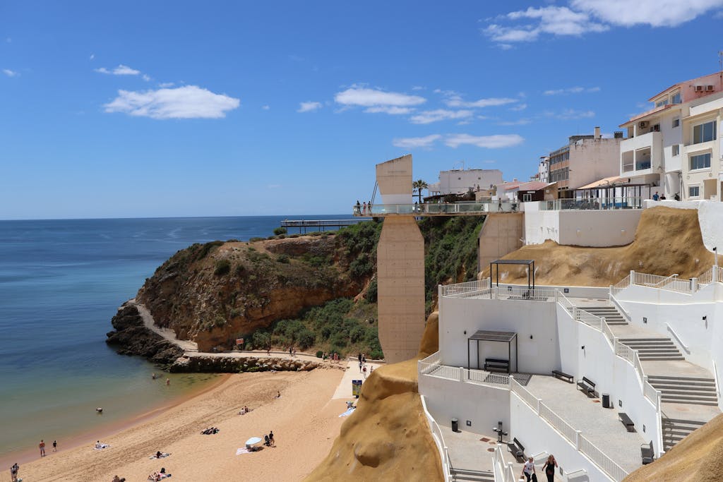 Beautiful seaside view in Algarve with cliffs and beachgoers on a sunny day.