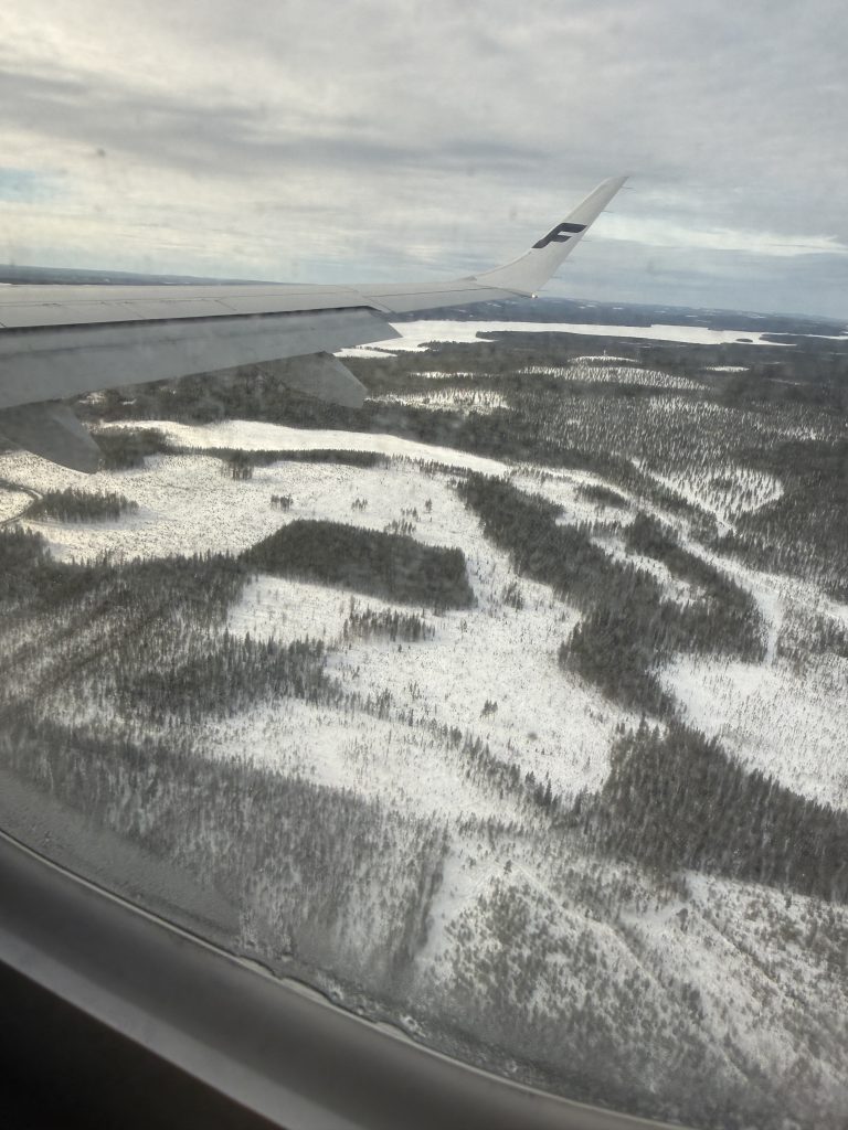 The Lapland terrain as seen out of a plane window when landing in Lapland. Fields of snow with birch and pine peaking out.