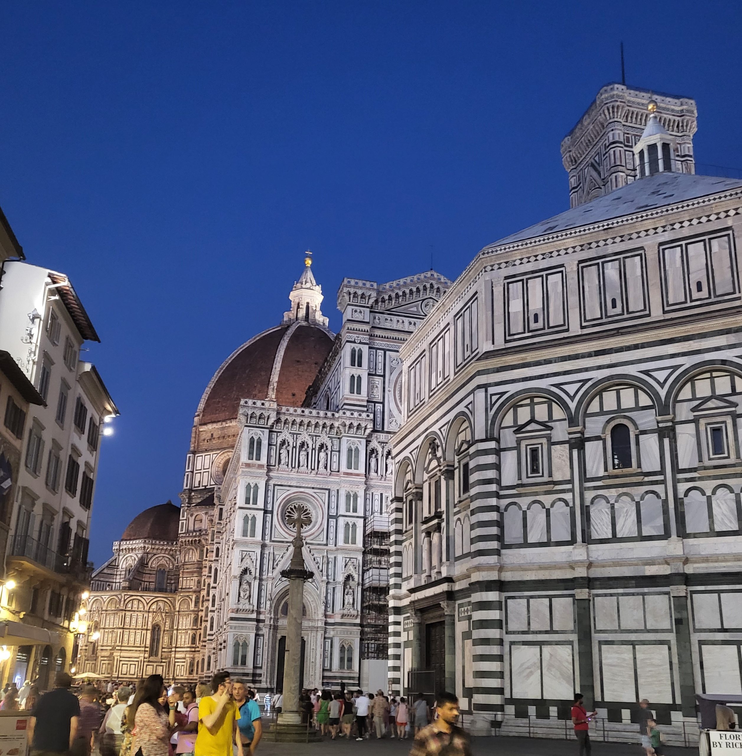 While looking for the hidden gems in Florence this is the Florence Cathedral as seen down a busy street on a clear night in July in Florence, Italy