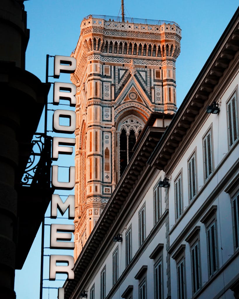 A vibrant view of Giotto's Campanile with sunset light and Profumeria sign in Florence, Italy.