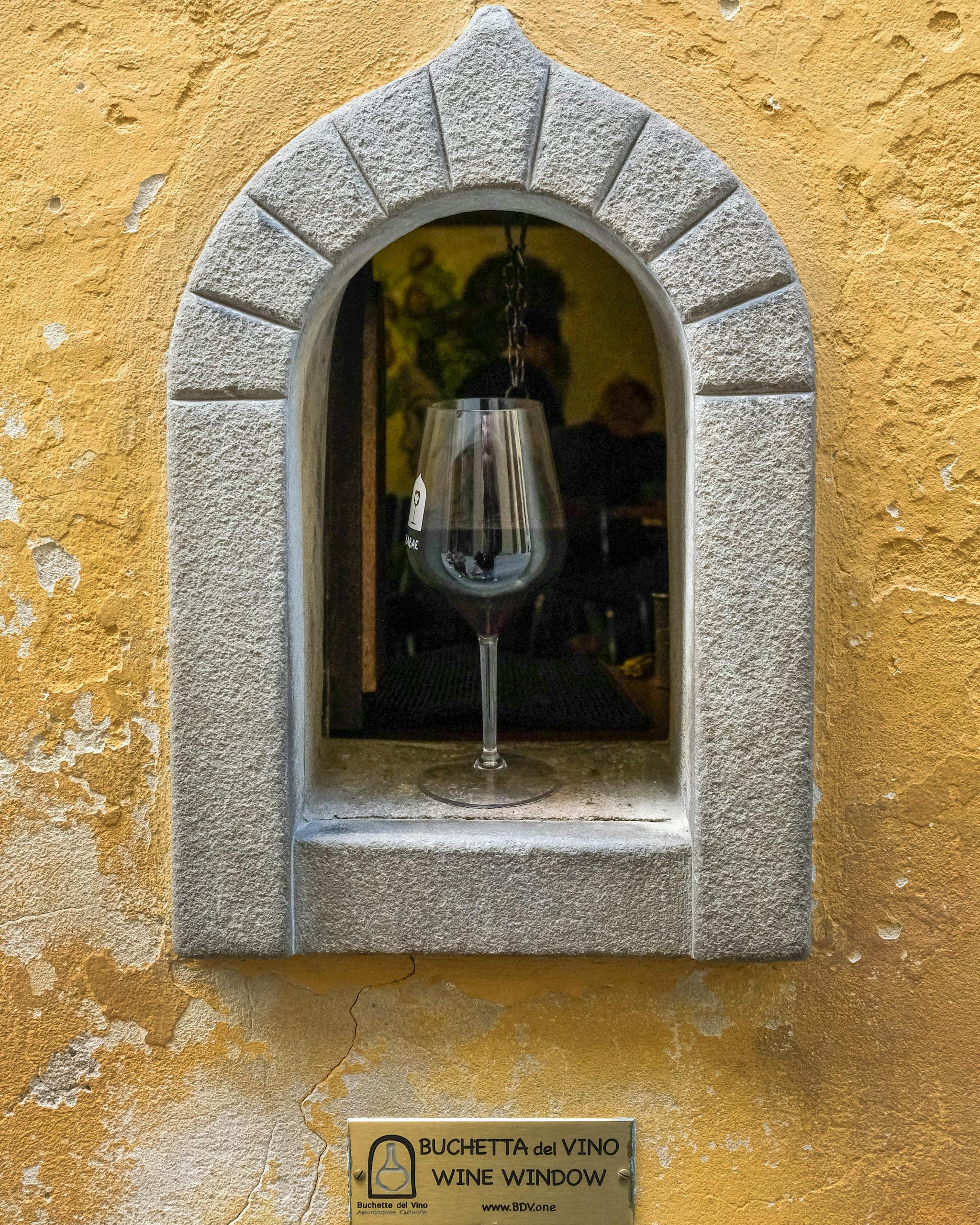 Close-up of a wine window with a glass of red wine in hidden gems in  Florence, Italy, showcasing Italian tradition. 
