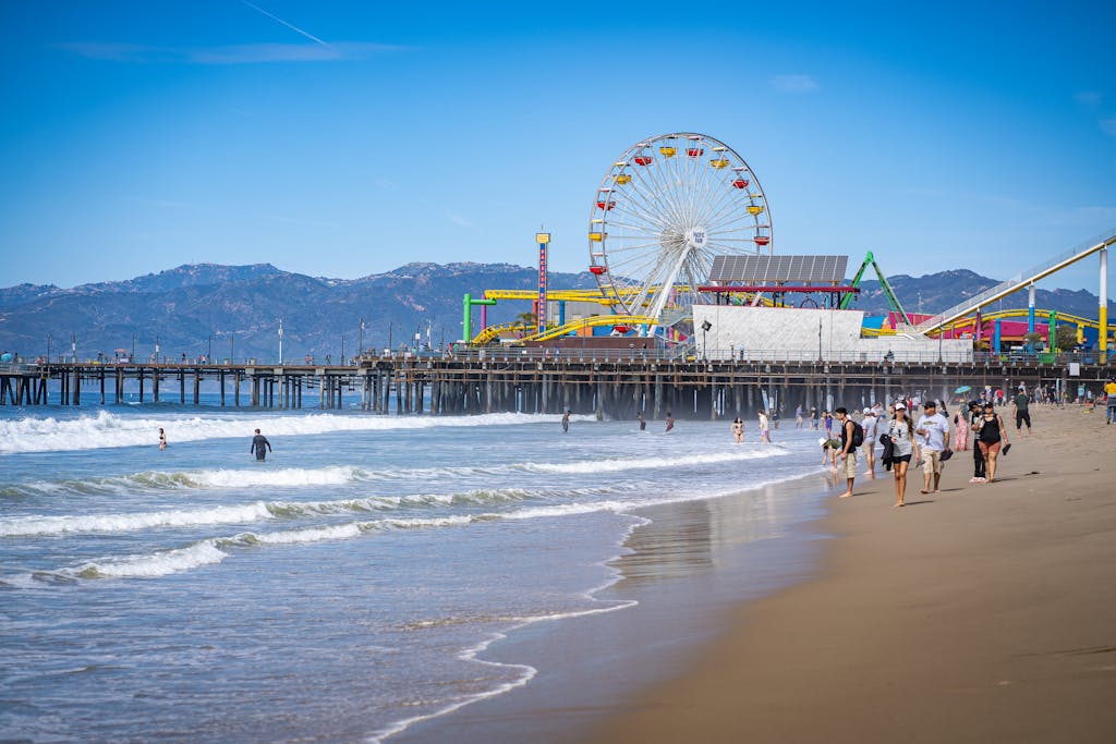 Scenic view of Santa Monica Pier with Ferris wheel, beach, and people enjoying a sunny day as seen in planning your LA 2028 Olympics trip