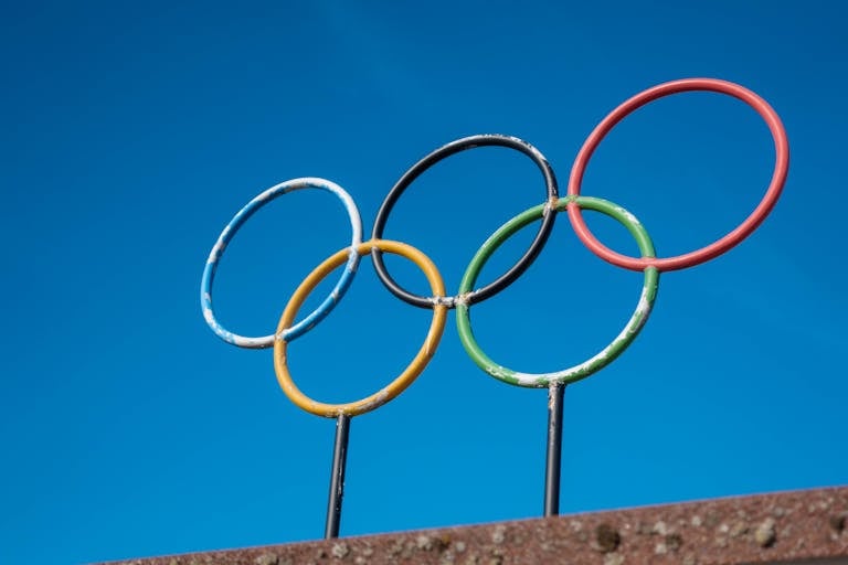 The iconic Olympic rings stand against a vibrant blue sky, symbolizing global unity and sportsmanship.