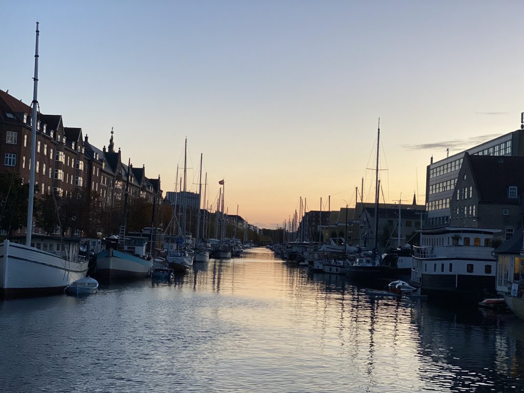 Copenhagen, Denmark waterway lined with buildings and boats as the sun is setting as seen in travel tips