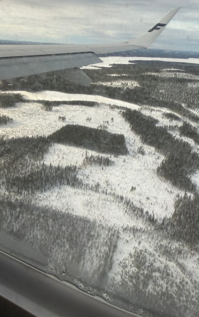 The Lapland terrain as seen out of a plane window when landing in Lapland. Fields of snow with birch and pine peaking out.