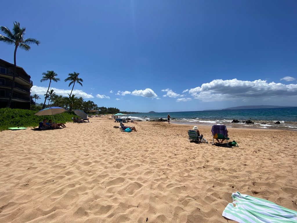 3 days in Maui enjoying the sunshine on a nice relaxing beach with a beautiful blue sky and clear ocean with several other people laying out on the warm sand
