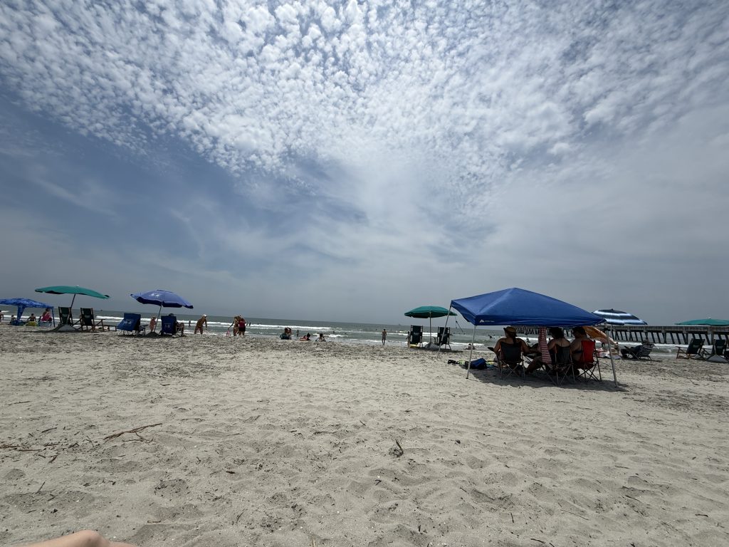 Folly Beach near Charleton, South Carolina on a summer day with people all over the beach and the hot sun shining down.