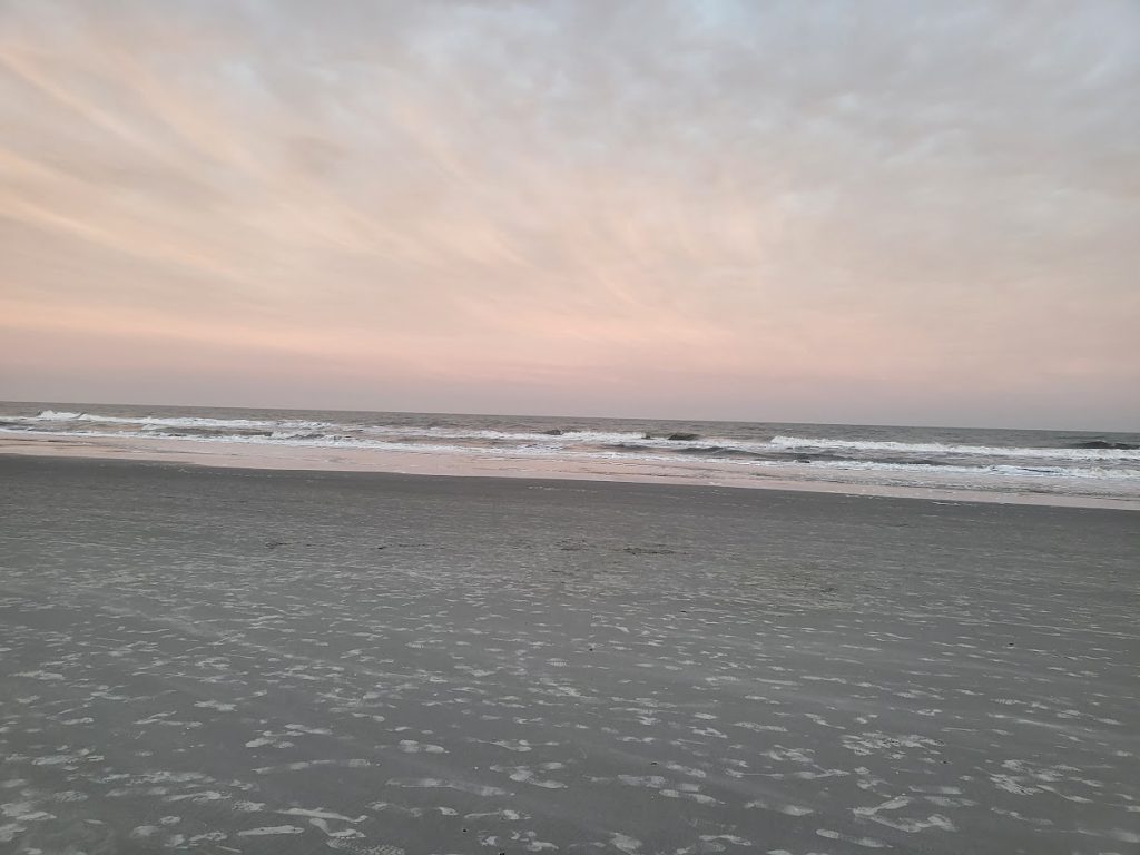 Looking at the water from the beach as the sun is setting in Charleston, SC as seen in things to do in charleston when its too hot