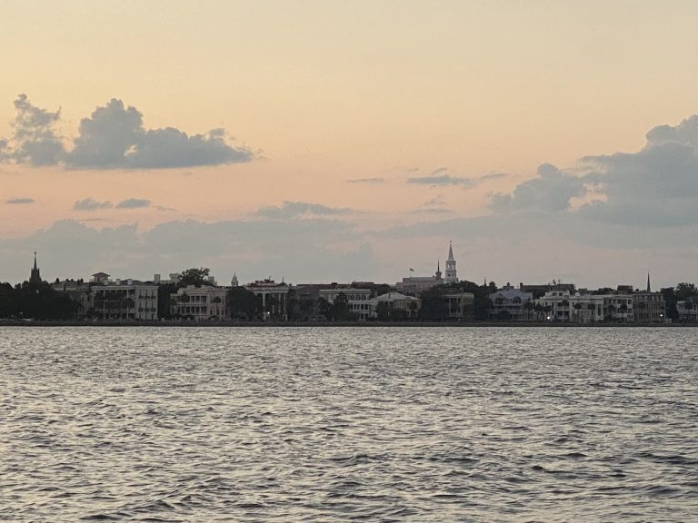Outline of downtown Charleston, South Carolina as the sun is setting as seen from a boat in the bay
